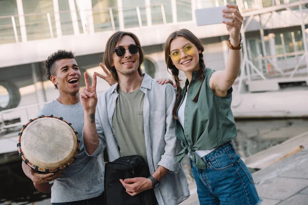 Team of young musicians with instruments taking selfie in urban environment — Stock Photo