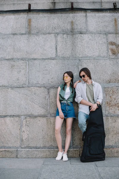 Menina se apoiando no homem com guitarra n ensolarado rua da cidade — Fotografia de Stock