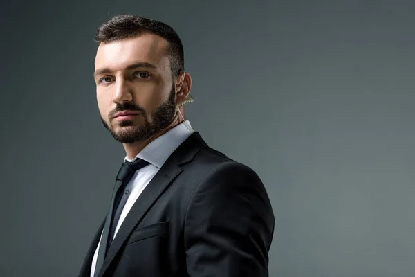 Handsome security guard with security earpiece looking at camera isolated on grey — Stock Photo