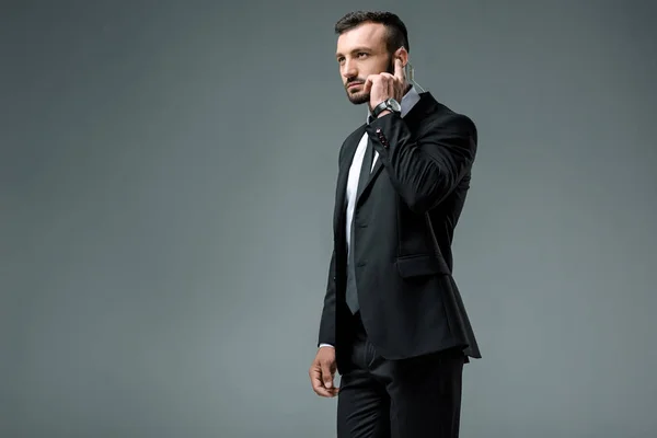 Handsome security guard listening message with security earpiece isolated on grey — Stock Photo