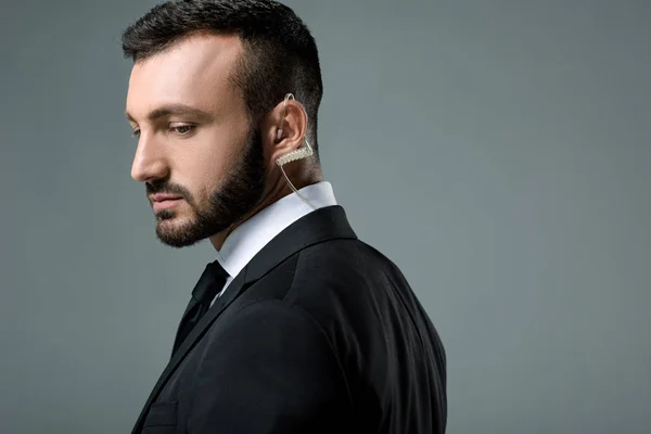 Side view of handsome security guard with security earpiece isolated on grey — Stock Photo