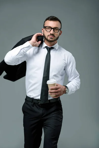 Bell'uomo d'affari che cammina con il caffè per andare isolato sul grigio — Foto stock