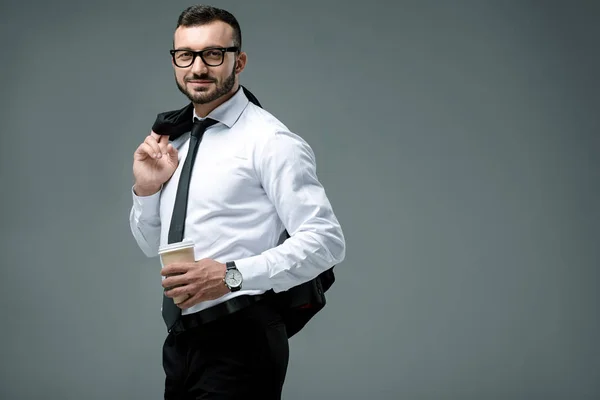 Schöner Geschäftsmann steht mit Kaffee in Pappbecher isoliert auf grau — Stockfoto