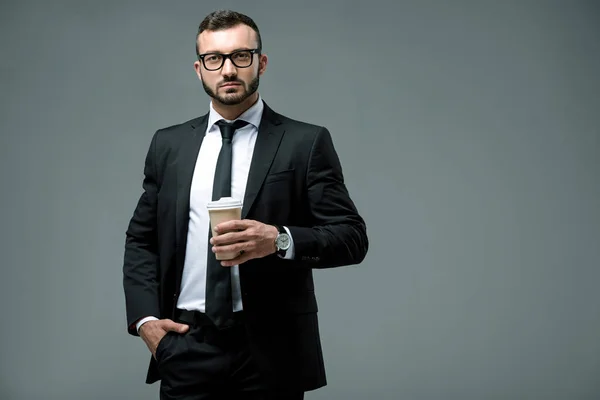 Schöner Geschäftsmann mit Einweg-Kaffeetasse isoliert auf grau — Stockfoto