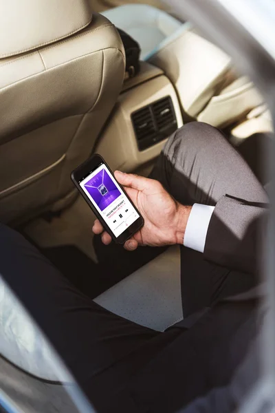 Cropped image of businessman holding smartphone and listening to fall out boy band in car — Stock Photo