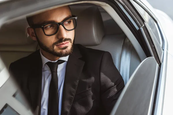 Bel homme d'affaires assis dans la voiture et regardant loin — Photo de stock