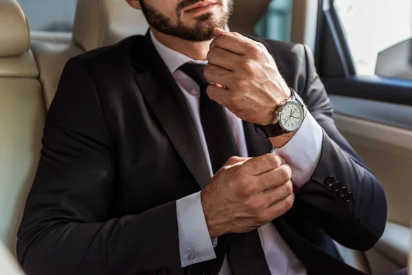 Imagem cortada de homem de negócios abotoando manguito no carro — Fotografia de Stock