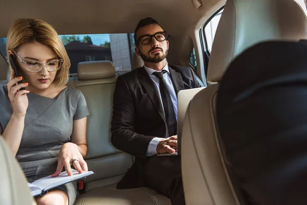 Businessman assistant talking by smartphone in car — Stock Photo