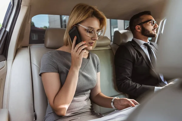 Attraktiver Geschäftsmann-Assistent, der im Auto per Smartphone spricht — Stockfoto