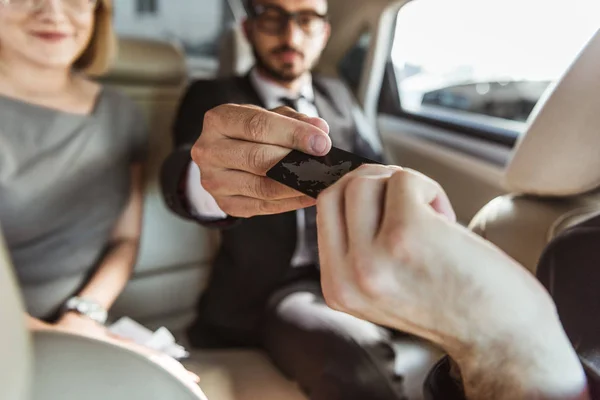 Empresario dando tarjeta de crédito al conductor para pagar el taxi - foto de stock