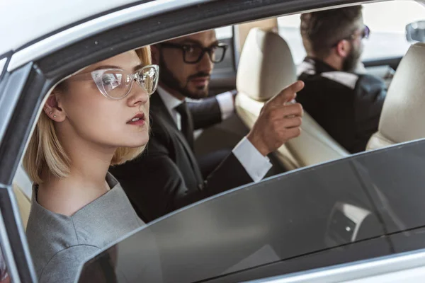 Gutaussehender Geschäftsmann zeigt auf Assistentin im Auto — Stockfoto