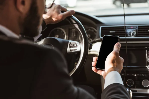 Cropped image of driver in suit driving car and holding smartphone — Stock Photo