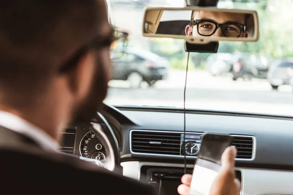 Handsome driver looking at mirror in car — Stock Photo