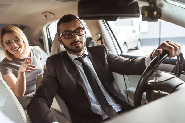 Businesswoman pointing on something to driver in car — Stock Photo