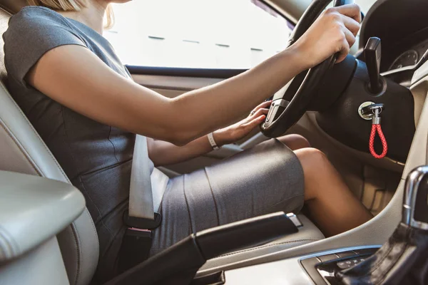 Abgeschnittenes Bild einer Geschäftsfrau im grauen Kleid, die Auto fährt — Stockfoto