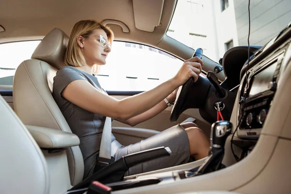 Vista de ángulo bajo de atractiva mujer de negocios coche de conducción - foto de stock