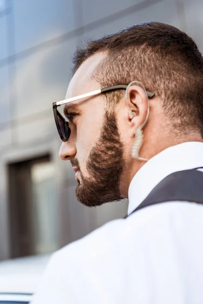 Vista lateral del guapo guardia de seguridad con auricular de seguridad en la calle - foto de stock