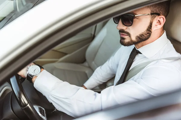 Seitenansicht des gutaussehenden Fahrers mit Sonnenbrille am Steuer — Stockfoto