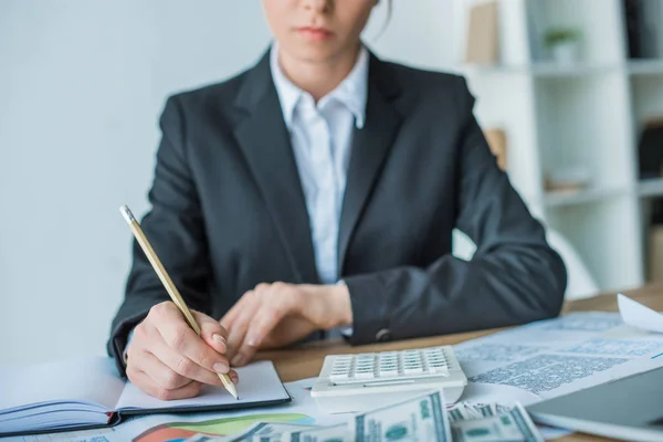 Abgeschnittenes Bild eines Finanziers, der im Büro etwas ans Notizbuch schreibt — Stockfoto