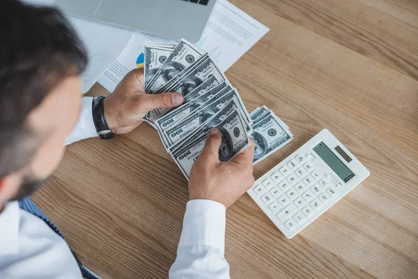 Image recadrée de financier comptant espèces avec calculatrice dans le bureau — Photo de stock