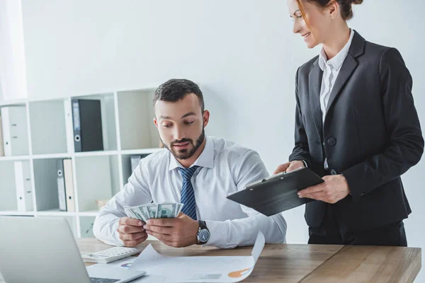 Attractive financier showing clipboard to colleague in office — Stock Photo