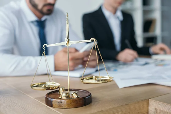 Financiers working in office with golden scales on foreground — Stock Photo