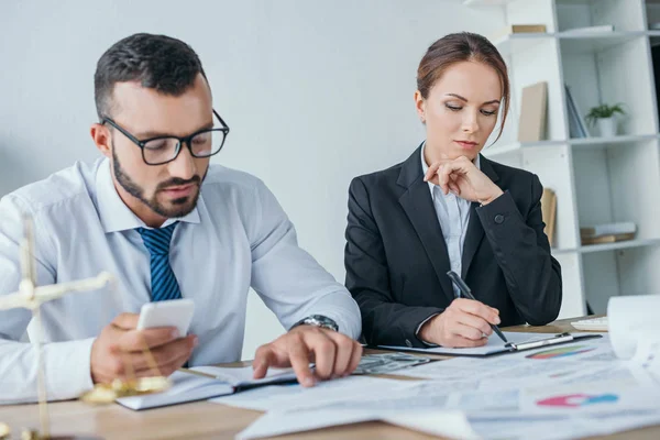 Buchhalter arbeiten mit Dokumenten und nutzen Smartphone im Büro — Stockfoto