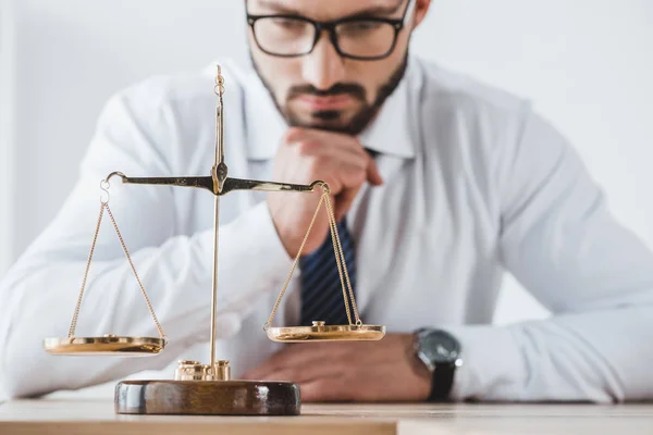 Pensive business adviser looking at scales with precision weights in office — Stock Photo