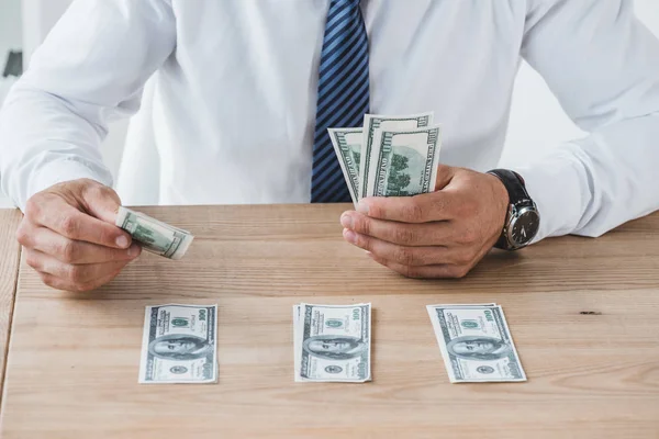 Immagine ritagliata del consulente aziendale che conta le banconote in dollari sul tavolo in carica — Foto stock