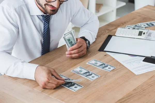 Imagem recortada do consultor de negócios contando notas de dólar na mesa no escritório — Fotografia de Stock