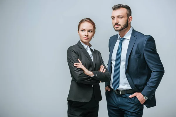 Mujer de negocios seria y hombre de negocios mirando hacia otro lado aislado en gris - foto de stock