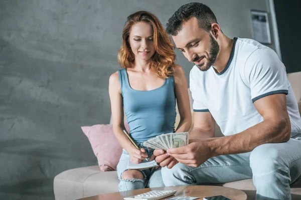 Planificación de pareja presupuesto familiar y contar el dinero en la sala de estar - foto de stock