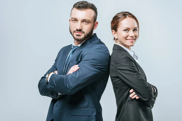 Donna d'affari e uomo d'affari sorridente in piedi con le braccia incrociate e guardando la fotocamera isolata su grigio — Foto stock