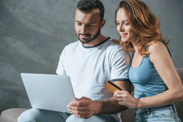 Casal feliz compras on-line com laptop e cartão de crédito em casa — Fotografia de Stock