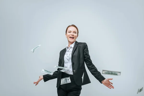 Attractive happy financier standing near falling dollars isolated on grey — Stock Photo