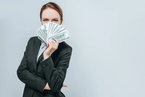 Hermoso financiero mirando hacia fuera de paquete de billetes de dólar aislados en gris - foto de stock