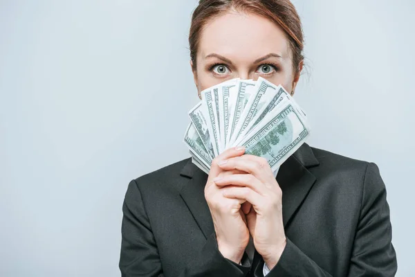 Attractive financier looking out from pack of dollar banknotes isolated on grey — Stock Photo