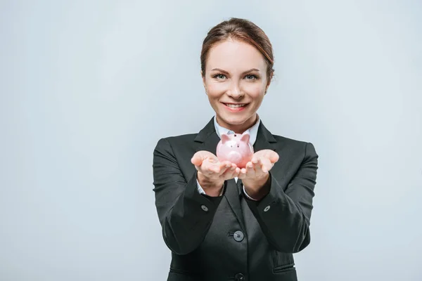 Smiling financier holding piggy bank isolated on grey — Stock Photo