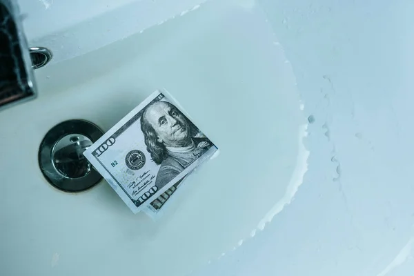 Vista superior da nota de dólar em água no lavatório — Fotografia de Stock