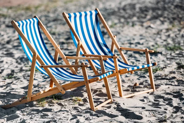 Striped beach chairs and cooler on sandy coast — Stock Photo