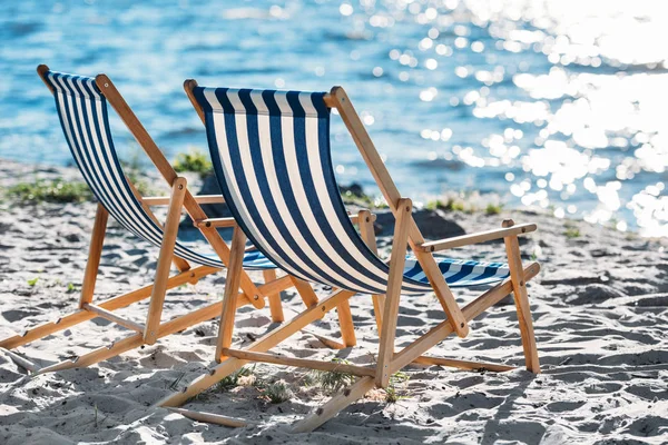 Salões de chaise listrados e refrigerador na praia arenosa — Fotografia de Stock