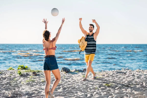 Happy young couple playing volleyball on sandy beach — Stock Photo