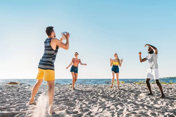 Happy young multiethnic friends playing beach volleyball — Stock Photo