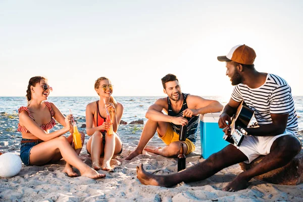 Happy young multiethnic friends spending time together on sandy beach — Stock Photo