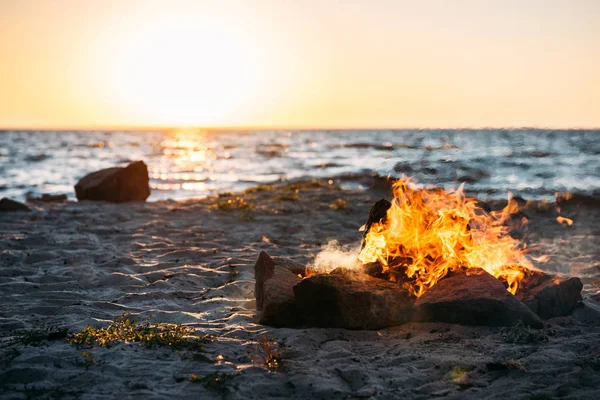 Bonfire on sandy sea coast at majestic sunset — Stock Photo