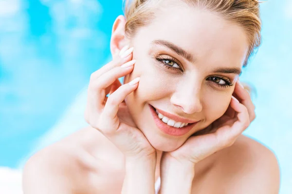 Porträt einer schönen jungen Frau, die am Pool in die Kamera lächelt — Stockfoto