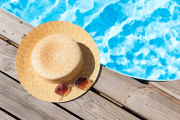 Close-up view of wicker hat and sunglasses near swimming pool — Stock Photo