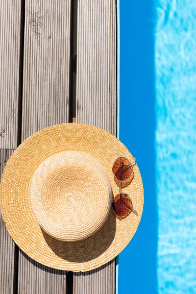 Top view of wicker hat and sunglasses near swimming pool — Stock Photo