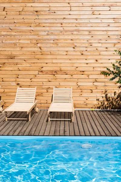Lounges de chaise acolhedores vazios perto da piscina com água transparente — Fotografia de Stock