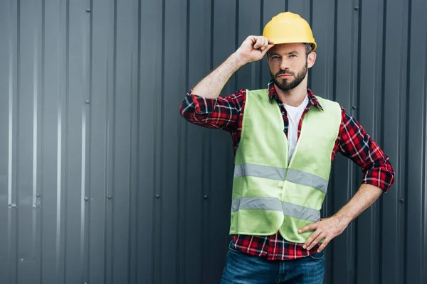 Male engineer in safety vest and helmet standing near wall — Stock Photo